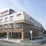 3階建ての介護施設の建物外観。淡色系の外壁で、1階に入口がある。